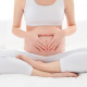 Pre-natal exercises. Beautiful pregnant woman exercising while sitting in lotus position